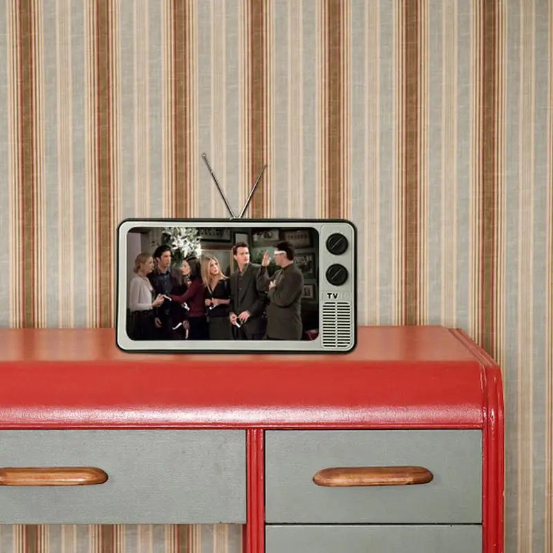 Screen Magnifier for Phones in silver retro TV style with black knobs on a red dresser