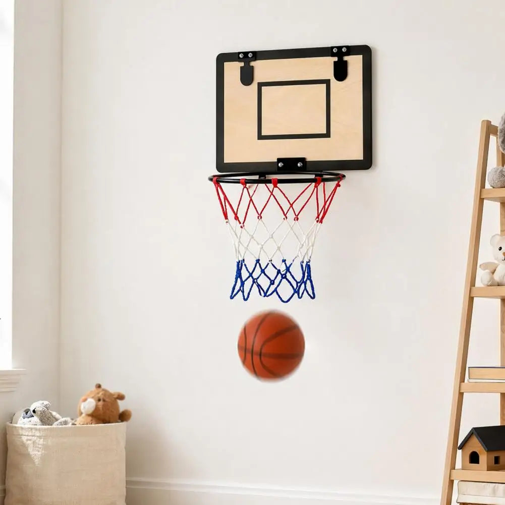 A wall-mounted mini basketball hoop with a beige backboard, black rim, red and blue net, and a basketball in motion below, shown in a bright room with a window, stuffed toys, and a wooden ladder shelf.
Laundry basket with bottom zipper for easy emptying