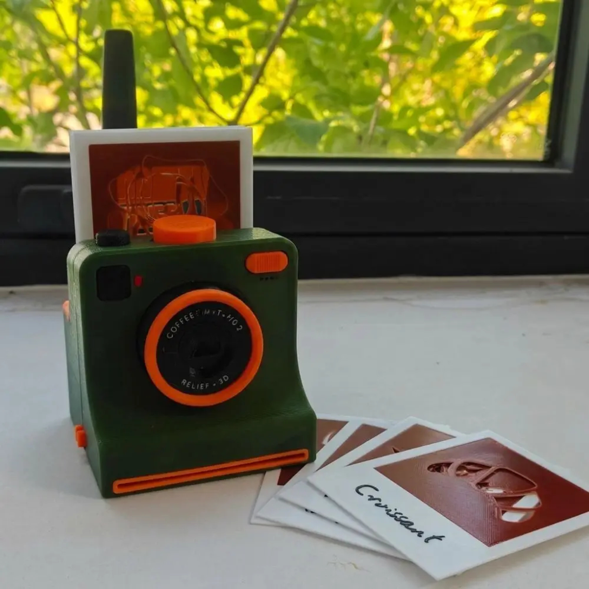 Green camera-shaped latte art stencil tool with interchangeable design cards